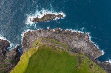 Stunning aerial shot capturing the rugged cliffs and deep blue ocean of the Faroe Islands. Perfect for travel and nature themes.