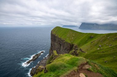 Yeşil kayalıkların ve Faroe Adaları 'ndaki Atlantik Okyanusu' nun yaz sonu manzarası doğa ve seyahat meraklıları için mükemmel..