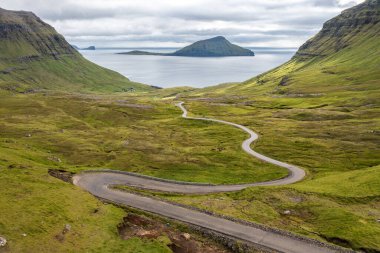 Faroe Adaları 'nın çarpıcı hava manzarası yemyeşil vadileri ve dolambaçlı yolları gösteriyor. Seyahat ve doğa temaları için mükemmel..