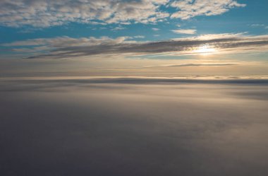 Faroe Adaları üzerinde sisli bir günbatımının nefes kesici panoramik görüntüsü, sakin bulutlar ve sakin bir gökyüzü sergiliyor..