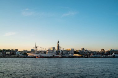 Gün batımında Hamburgs limanının nefes kesici manzarası ikonik saat kulesi ve canlı şehir manzarasını gözler önüne seriyor..