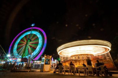 Geceleri Turia Park 'ın hareketli atmosferini tecrübe edin. Renkli bir dönme dolap ve dönen bir atlıkarınca. Sihirli anları yakalamak için mükemmel..
