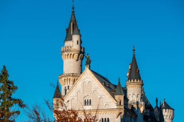 Neuschwanstein Kalesi 'nin büyüleyici güzelliğini keşfedin. Almanya, Bavyera' da canlı bir mavi gökyüzüne karşı kurulmuş..