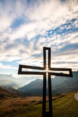 Dramatik bulutlar ve İtalya 'daki çarpıcı Alpler manzarasıyla çerçevelenmiş güzel bir haç silueti. Manevi ve doğa temaları için mükemmel..