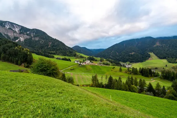 İtalya, Lago di Braies 'in büyüleyici güzelliğini tecrübe edin. Bulutlu bir gökyüzünün altında yemyeşil ve görkemli dağlar sergiliyor..