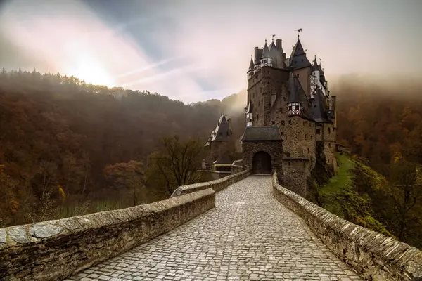 Eltz Şatosu 'nun nefes kesici güzelliğini tecrübe edin. Canlı sonbahar yaprakları ve sisli dağlarla çevrili..