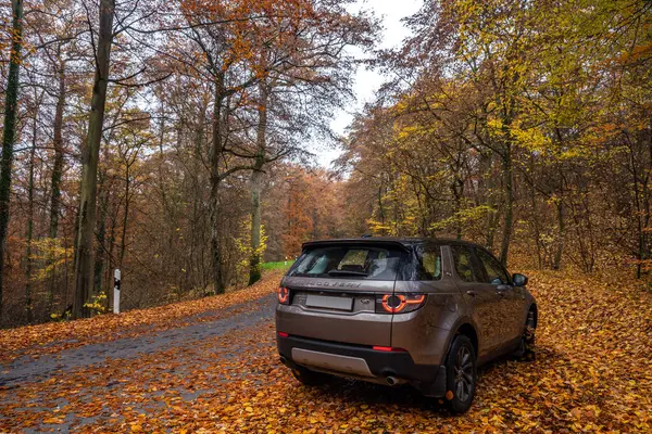 Eltz Şatosu 'nun yanında renkli bir sonbahar manzarası manzaralı bir yola park edilmiş şık bir araba. Seyahat ve macera temaları için mükemmel.