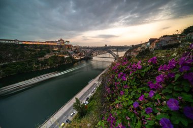 Porto, Portekiz 'deki Douro Nehri üzerinde nefes kesici günbatımı manzarası canlı çiçekler ve ikonik mimari sergiliyor..