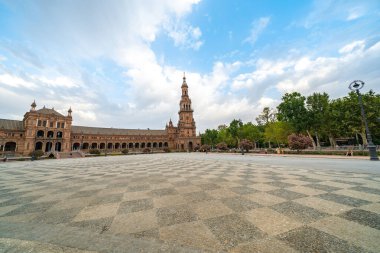 Sevilla 'daki Plaza de Espaa' nın çarpıcı manzarası dinamik bir gökyüzüne karşı görkemli mimarisini tasvir ediyor..