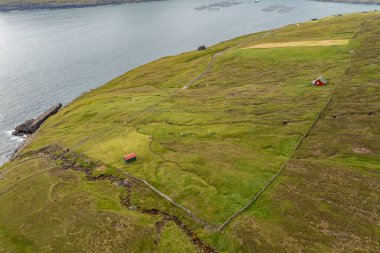 Geniş bir hava görüntüsü, Faroe Adaları 'nın canlı yeşil tepelerini ve dingin sularını yakalayarak doğal güzelliğini ve huzurunu gözler önüne seriyor..