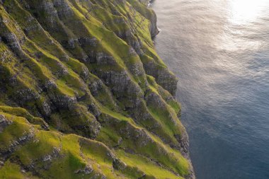 Sersemletici insansız hava aracı görüntüsü, verimli yeşil tepeleri ve Faroe Adaları 'nın kayalık sahil şeridini gözler önüne seriyor, doğa meraklıları ve seyahat fotoğrafçıları için mükemmel..
