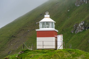 Yazın sonlarında Faroe Adaları 'nda yemyeşil bir deniz fenerinin göz kamaştırıcı manzarası.