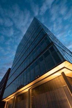 Almanya, Hamburg 'da canlı bir yaz günbatımında çekilmiş çarpıcı bir modern cam bina fotoğrafı..