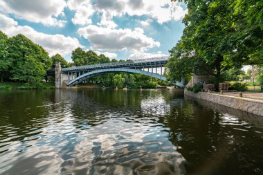 Çarpıcı bir yaz sahnesi, Hamburg 'un sakin sularını yansıtan bir köprüyü yakalıyor, yemyeşil ve güzel bir gökyüzü ile çevrili..
