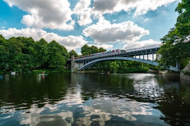 Hamburg 'daki bir köprünün manzarası yaz sıcağını yansıtıyor, su ve geçen bir trenin yansımalarıyla..