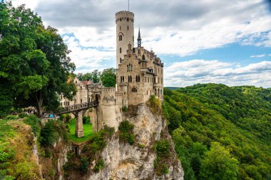 Almanların yemyeşil ve mavi gökyüzünde görkemli bir uçurumun üzerindeki tarihi bir şatonun çarpıcı yaz manzarası.