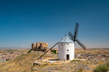 İspanya 'da açık bir yaz gökyüzüne çarpan tarihi Consuegra rüzgar değirmenlerinin nefes kesici manzarası.