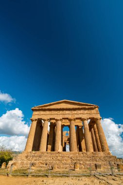 İtalya, Sicilya 'daki nefes kesici antik Yunan tapınağı kalıntılarını keşfedin, çarpıcı mavi gökyüzü altında tüylü bulutlarla yıkanan.