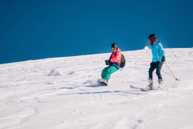 Karpaty, Ukraine, February 8, 2023. Skiers and snowboarders freeride in clear sunny weather on the slopes of the mountains near the resort of Dragobrat. High quality photo