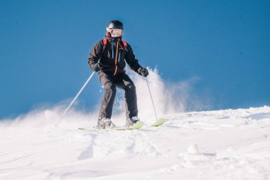 Karpaty, Ukraine, February 8, 2023. Skiers and snowboarders freeride in clear sunny weather on the slopes of the mountains near the resort of Dragobrat. High quality photo