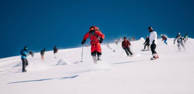 Karpaty, Ukraine, February 8, 2023. Skiers and snowboarders freeride in clear sunny weather on the slopes of the mountains near the resort of Dragobrat. High quality photo