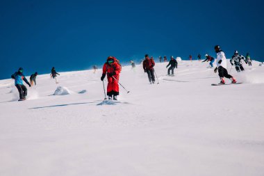 Karpaty, Ukraine, February 8, 2023. Skiers and snowboarders freeride in clear sunny weather on the slopes of the mountains near the resort of Dragobrat. High quality photo
