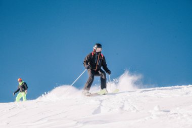 Karpaty, Ukraine, February 8, 2023. Skiers and snowboarders freeride in clear sunny weather on the slopes of the mountains near the resort of Dragobrat. High quality photo
