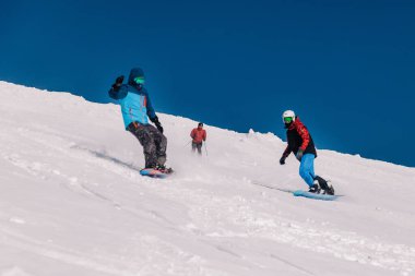 Karpaty, Ukrayna, 8 Şubat 2023. Kayakçılar ve snowboardcular, Dragobrat tatil beldesi yakınlarındaki dağların yamaçlarında açık güneşli havada serbest dolaşırlar. Yüksek kalite fotoğraf