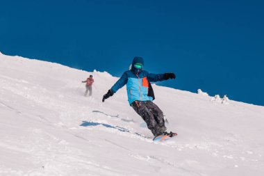 Karpaty, Ukrayna, 8 Şubat 2023. Kayakçılar ve snowboardcular, Dragobrat tatil beldesi yakınlarındaki dağların yamaçlarında açık güneşli havada serbest dolaşırlar. Yüksek kalite fotoğraf