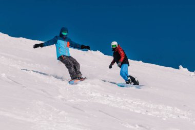 Karpaty, Ukrayna, 8 Şubat 2023. Kayakçılar ve snowboardcular, Dragobrat tatil beldesi yakınlarındaki dağların yamaçlarında açık güneşli havada serbest dolaşırlar. Yüksek kalite fotoğraf