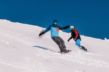 Karpaty, Ukrayna, 8 Şubat 2023. Kayakçılar ve snowboardcular, Dragobrat tatil beldesi yakınlarındaki dağların yamaçlarında açık güneşli havada serbest dolaşırlar. Yüksek kalite fotoğraf