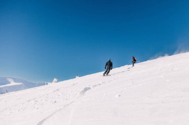 Karpaty, Ukraine, February 8, 2023. Skiers and snowboarders freeride in clear sunny weather on the slopes of the mountains near the resort of Dragobrat. High quality photo
