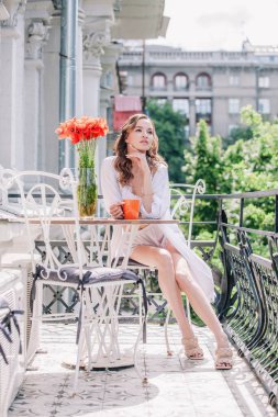 Düğünden önce beyaz dantelli iç çamaşırlarıyla genç, narin bir gelin bir otel odasının balkonunda otururken portakallı fincandan kahve içiyor. Yüksek kalite fotoğraf