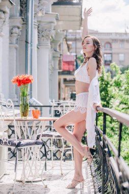 Genç, narin, güzel gelin sabah düğün balkonda güzel beyaz dantelli iç çamaşırlarıyla dikilmeden önce. Yüksek kalite fotoğraf