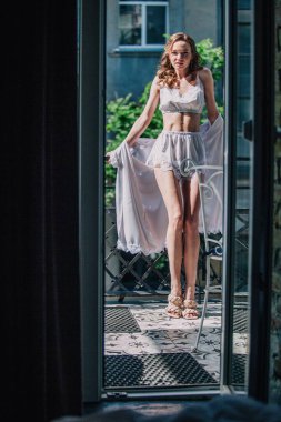 Genç, narin, güzel gelin sabah düğün balkonda güzel beyaz dantelli iç çamaşırlarıyla dikilmeden önce. Yüksek kalite fotoğraf