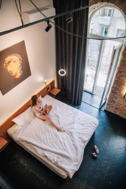 Genç, güzel bir gelin, sabahleyin otel odasında uzanmadan önce beyaz dantelli iç çamaşırlarıyla. Yüksek kalite fotoğraf