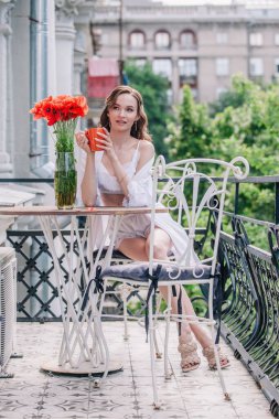 Düğünden önce beyaz dantelli iç çamaşırlarıyla genç, narin bir gelin bir otel odasının balkonunda otururken portakallı fincandan kahve içiyor. Yüksek kalite fotoğraf