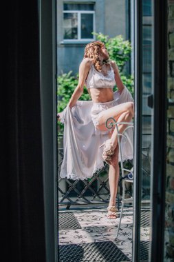 Genç, narin, güzel gelin sabah düğün balkonda güzel beyaz dantelli iç çamaşırlarıyla dikilmeden önce. Yüksek kalite fotoğraf