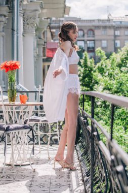 Genç, narin, güzel gelin sabah düğün balkonda güzel beyaz dantelli iç çamaşırlarıyla dikilmeden önce. Yüksek kalite fotoğraf