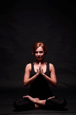 Siyah mauka ve siyah şortlu, siyah saçlı, siyah stüdyo geçmişinde yoga yapan zayıf atletik kız. Yüksek kalite fotoğraf