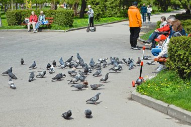 Rivne, Ukrayna, 5 Mayıs 2022: İnsanlar şehir parkında dinleniyor ve güvercinleri besliyor