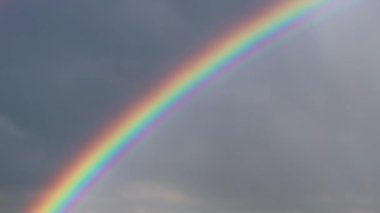 Gökkuşağının parlak doğal renkleri koyu yağmur bulutlarının arka planında
