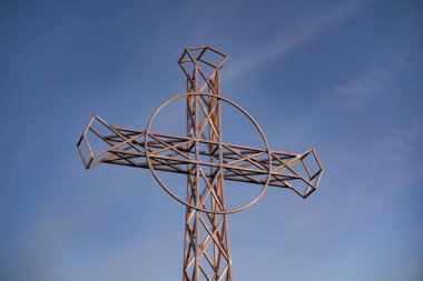 Tarnica tepesinde soğuk bir kasım günbatımında sembolik bir haç, Bieszczady Dağları manzaralı ve bulutlu mavi gökyüzü.