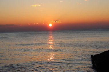 Camogli, Italy - January 27, 2023: Beautiful old mediterranean town at the sunrise time with illumination during winter days.People enjoying the evening at the beach with beautiful sunset background