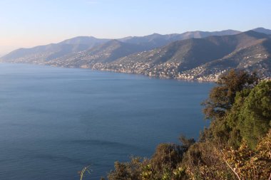 Camogli, Italy - January 27, 2023: Beautiful old mediterranean town at the sunrise time with illumination during winter days. People enjoying the evening at the beach with beautiful sunset background