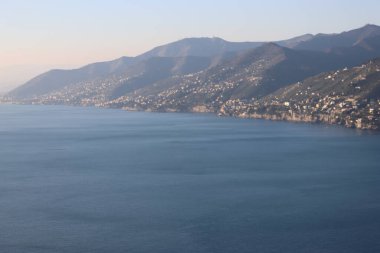 Camogli, Italy - January 27, 2023: Beautiful old mediterranean town at the sunrise time with illumination during winter days. People enjoying the evening at the beach with beautiful sunset background