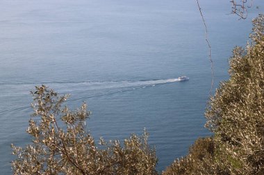 Camogli, Italy - January 27, 2023: Beautiful old mediterranean town at the sunrise time with illumination during winter days. People enjoying the evening at the beach with beautiful sunset background