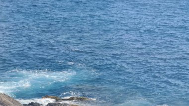 Cenova, İtalya - 11 Mayıs 2023: Baharda güzel deniz manzarası. Mavi gökyüzü sıcak hava ve sakin deniz. Akdeniz manzarası renkleri. Kayaların yanında küçük dalgalar.