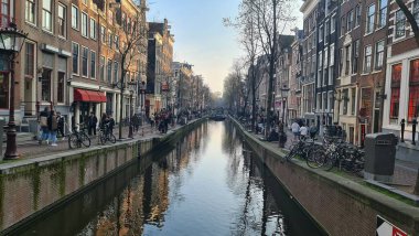 Amsterdam, Hollanda - 22 Nisan 2023: İlkbahar günlerinde Amsterdam 'ı keşfetmek. Amstel nehri etrafında bisiklet sürmek, eski evler ve şehrin eski kısmının güzel manzarası..