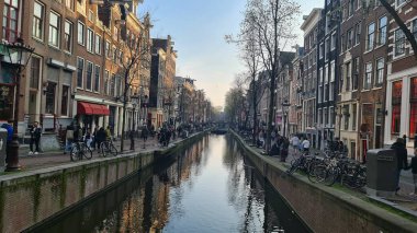Amsterdam, Hollanda - 22 Nisan 2023: İlkbahar günlerinde Amsterdam 'ı keşfetmek. Amstel nehri etrafında bisiklet sürmek, eski evler ve şehrin eski kısmının güzel manzarası..